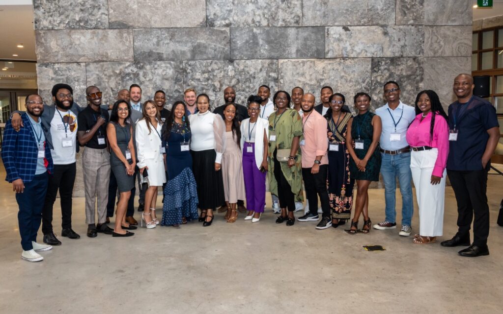 A group of people standing in front of a grey wall