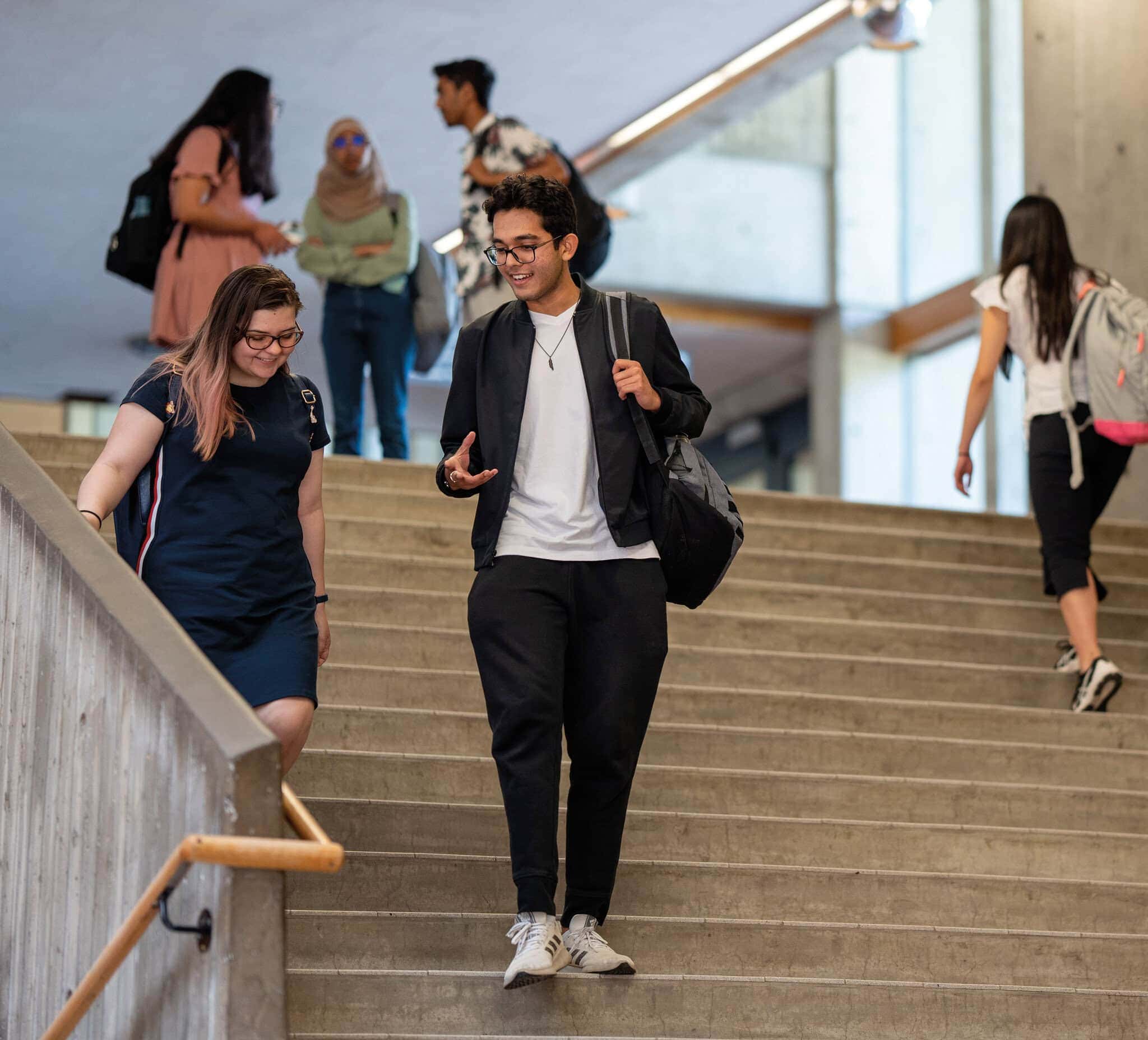 Two students chatting going down a staircase.