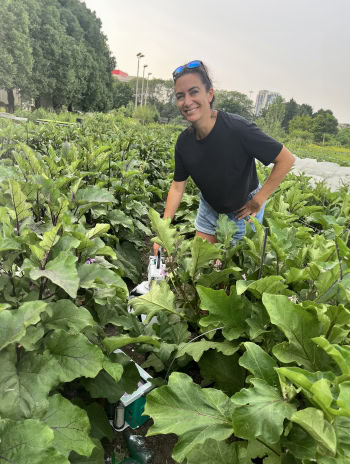 A woman standing in a vegetable patch looking happy