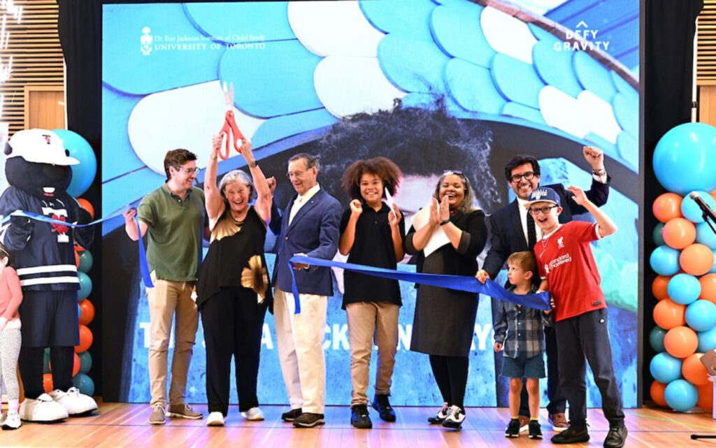 A group of people on stage smiling and cutting a ribbon