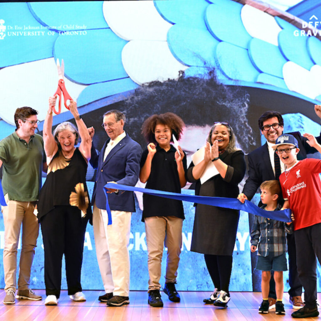 A group of people cutting a ribbon on a stage and smiling