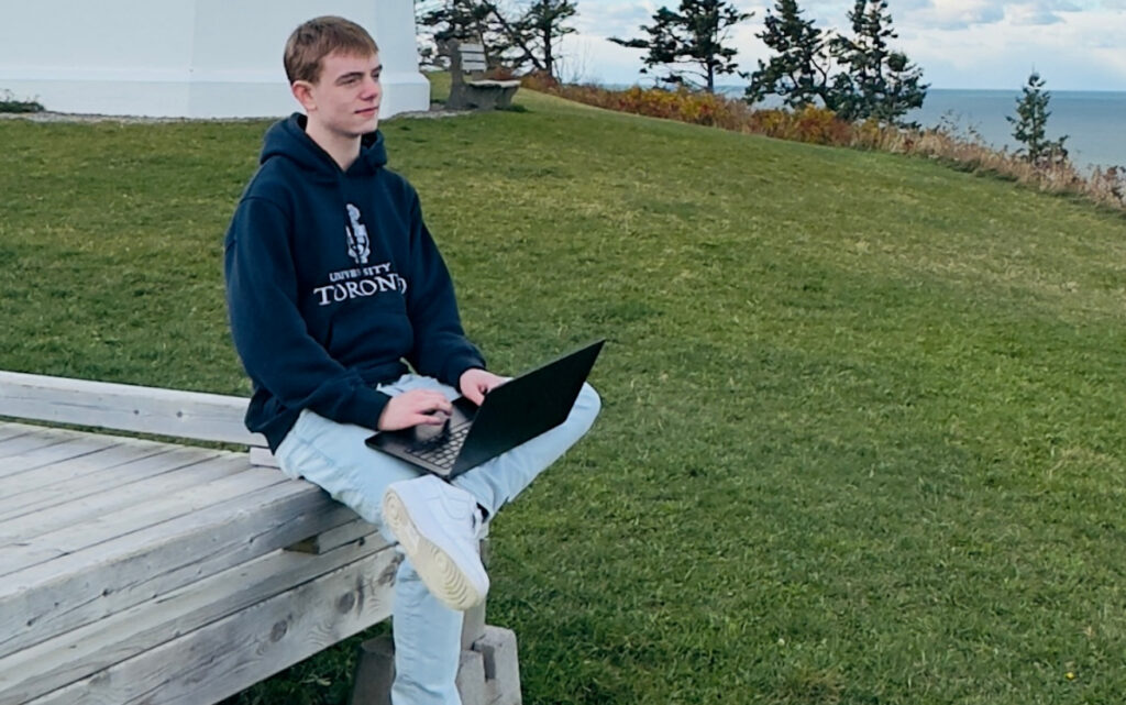 Caleb sitting outside with a laptop