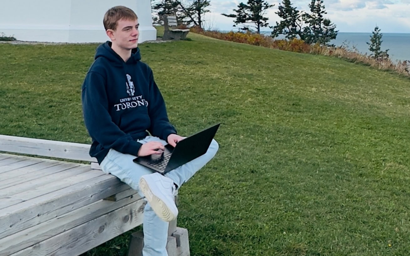 Caleb sitting outside with a laptop