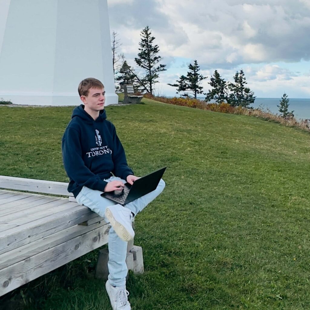 Caleb sitting outdoors with a laptop