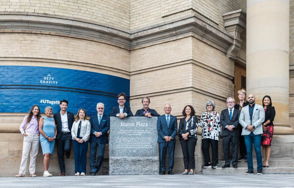 Photo of the University of Toronto Association in front  of the Alumni Plaza sign