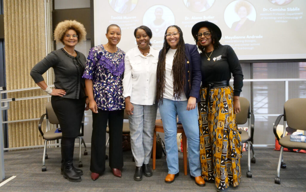 Five women posing together and smiling