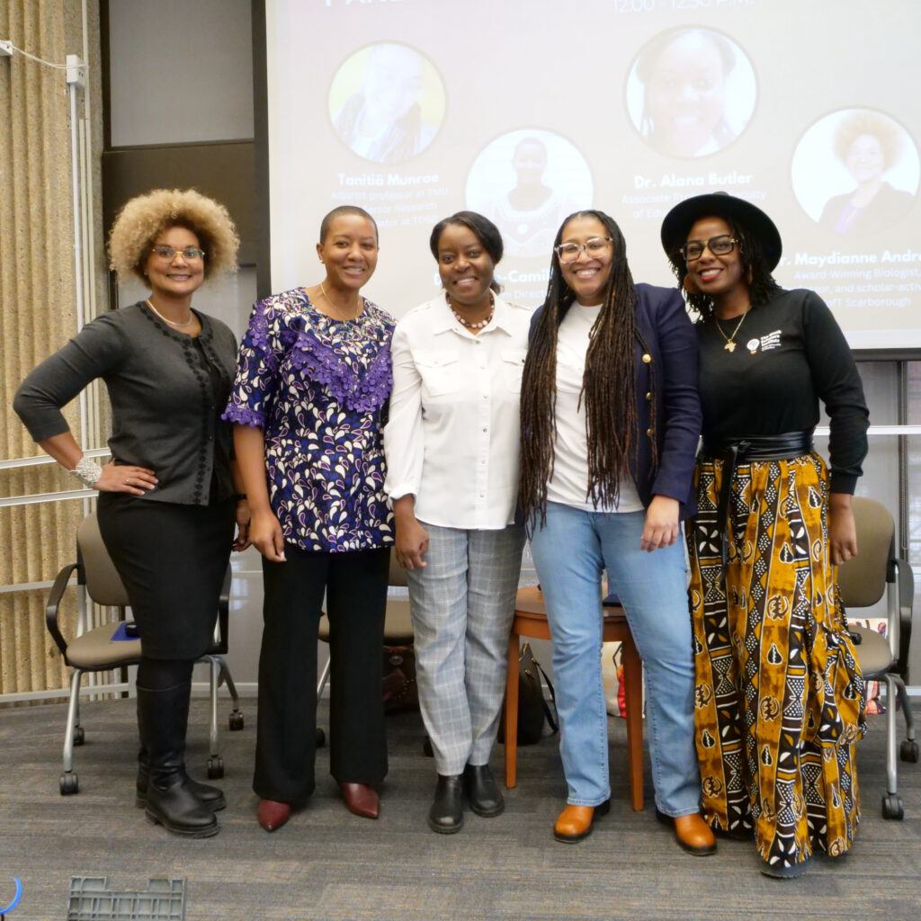 Five women posing together and smiling