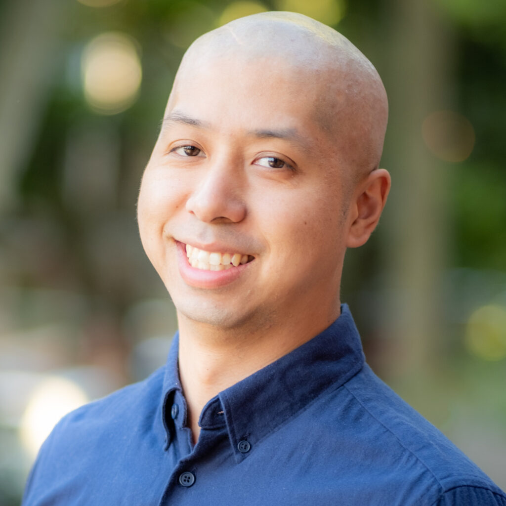 A portrait of Jimmy Lu wearing a blue shirt and smiling.