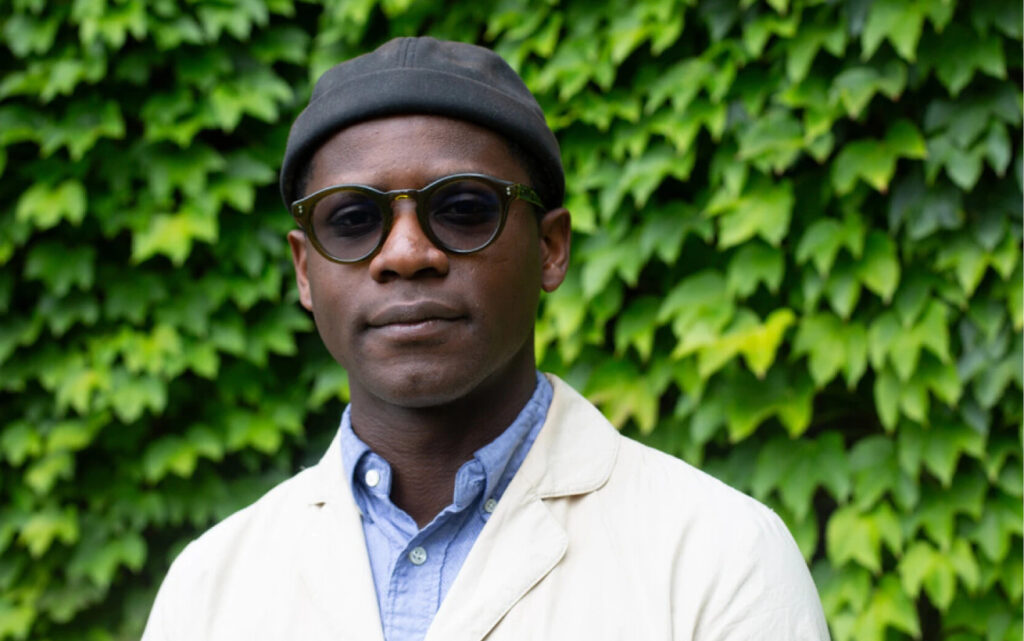A portrait of Michael standing in front of some greenery