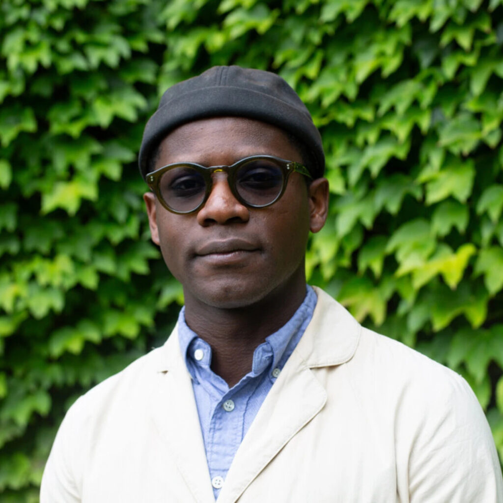 A portrait of Michael standing in front of some greenery