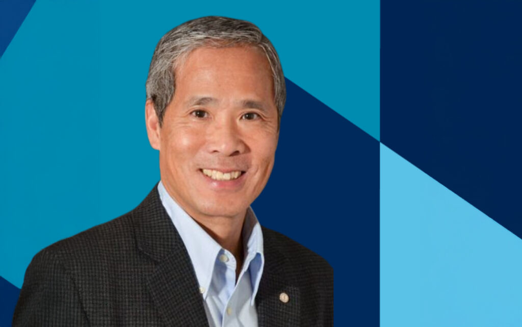 A portrait of a man in front of a graphic blue backdrop