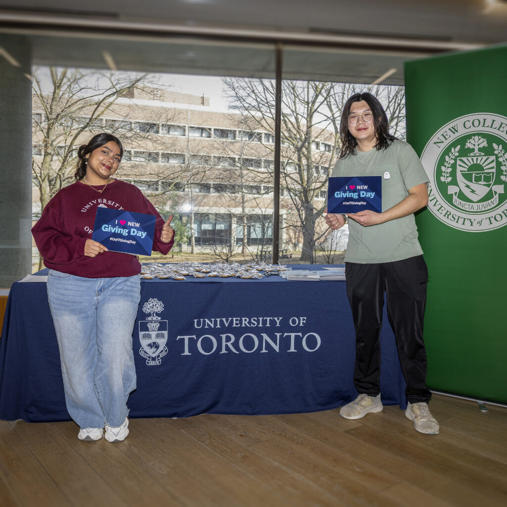 New College students posing by a Giving Day booth with table signage and an New College banner signage