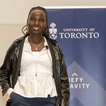 A woman posing in front of a U of T banner
